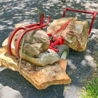 Red mechanical device lifting large stones on a road