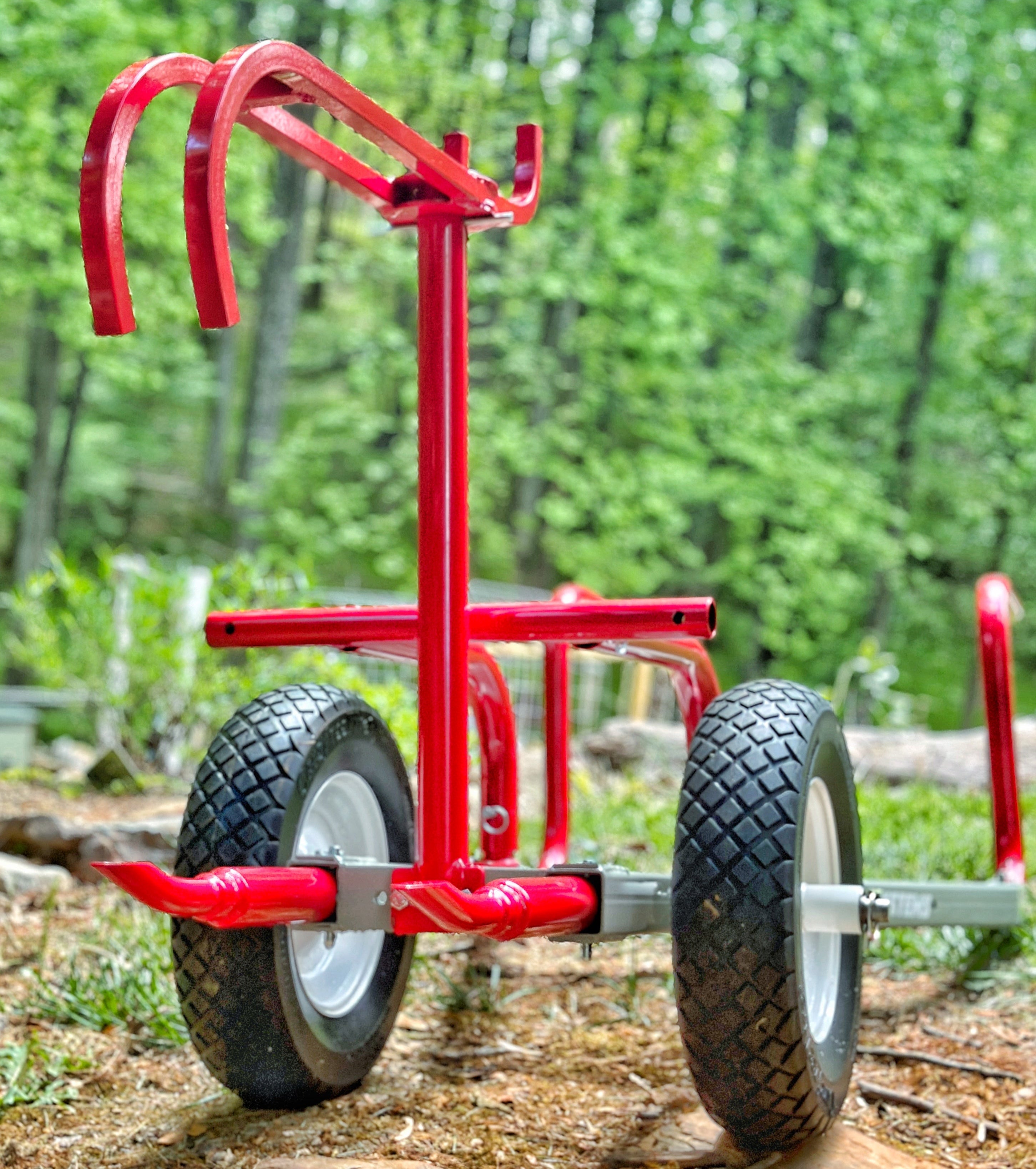 Red metal cart with large wheels on a forest floor