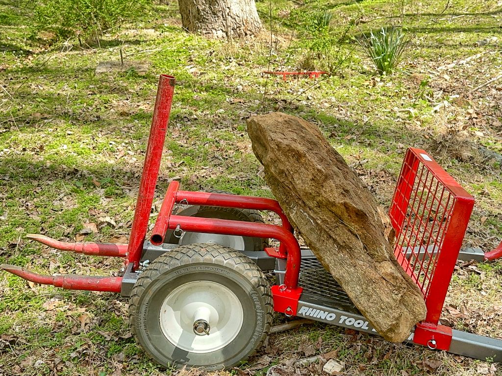 Red tree removal tool with a large rock on a grassy area
