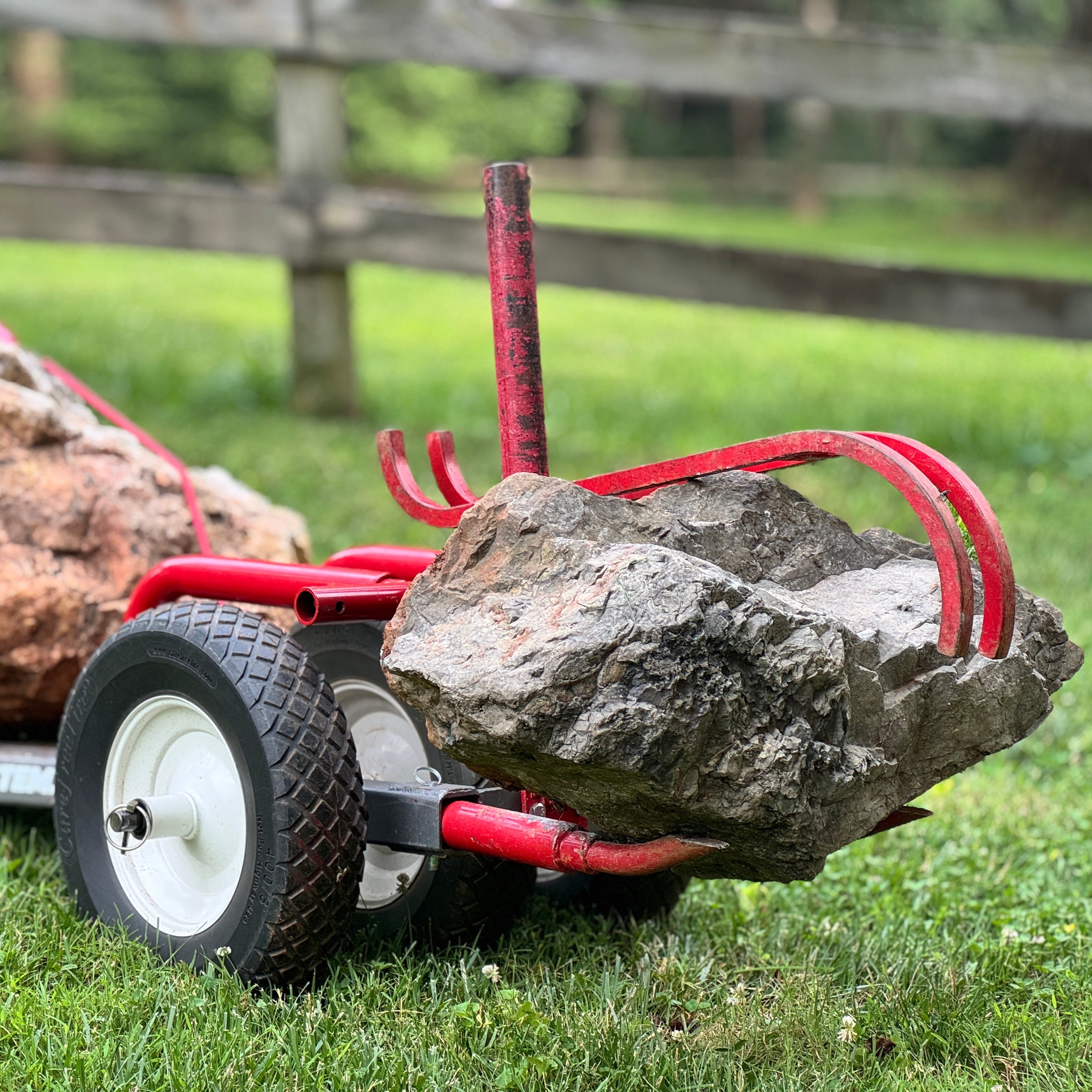 Red rock mover with two large rocks on a grassy area